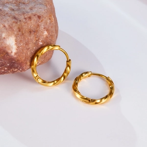 Detailed macro view of golden twisted Mobius hoop earrings on a white stand