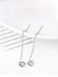 Close-up of heart-shaped pendant on long 18K gold titanium steel drop earrings