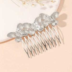 Detailed macro view of three connected silver butterfly ornaments on a vintage hair comb