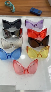 Flat lay of oversized Y2K punk shield sunglasses in various vibrant colors on white surface