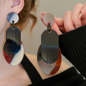 Détail de boucles d'oreilles géométriques en acrylique avec blocs de résine blancs