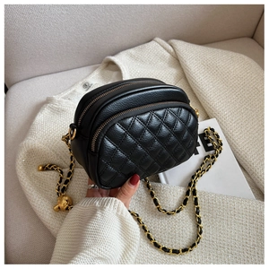 Detail of black quilted leather camera bag with dual zippers and gold chain strap