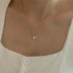 Close-up of elegant gold necklace with teardrop and round cubic zirconia on a model