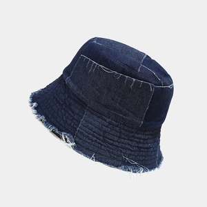 Detail view of denim bucket hat showing irregular stitching and distressed frayed edges