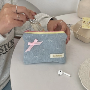 Macro view of blue denim coin purse featuring heart embroidery and pink silk bow detail