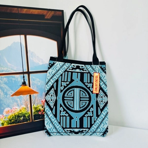 Detail of blue and black geometric knit tote bag with durable woven texture and black straps