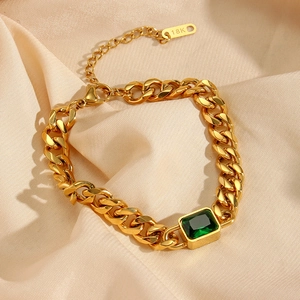Macro detail of 18K gold-plated Cuban chain bracelet with rectangular green gemstone