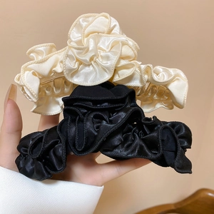 Detail of a large hair claw clip set with pleated satin fabric in cream and black colors