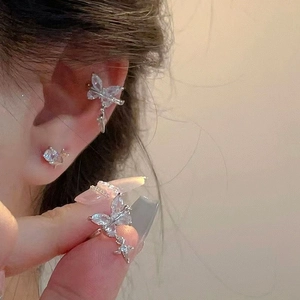 Detailed macro close-up of sparkling zircon butterfly ear cuff and star earring set