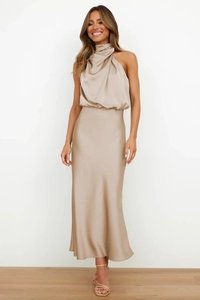 Detail of elegant champagne satin maxi dress showing halter neck and draped neckline texture
