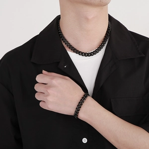 Close-up of sleek black Cuban link chain necklace and bracelet set on male model
