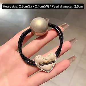 Détail de perle nacrée et breloque coeur en cuir sur élastique à cheveux noir robuste