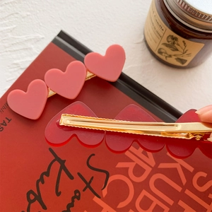 Cute pink and red heart acrylic duckbill hair clips on white aesthetic background