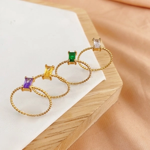 Set of four gold twisted band rings featuring emerald-cut colorful gemstones on silk