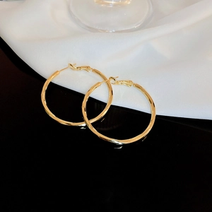 Macro detail of gold plated hoop earrings with flat multi-faceted metallic surface