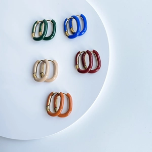Macro shot of U-shaped gold plated earrings with colorful enamel dripping finishes