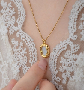 Macro shot of gold oval pendant with white mother of pearl inlay and lava texture