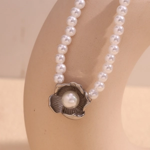 Close-up of pearl necklace featuring a large faux pearl in a silver flower pendant detail