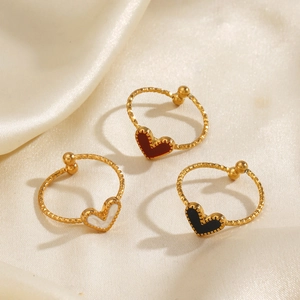 Three minimalist gold heart rings with red white and black charms on silk fabric