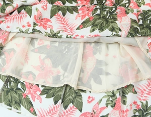 Détail de robe en mousseline fleurie avec motif d'oiseaux roses et doublure opaque