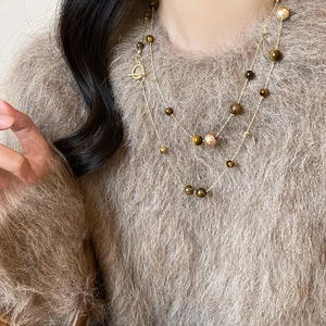 Detailed close-up of tiger eye bead and pearl layered necklace with gold toggle clasp