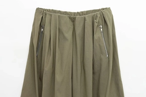Detail of olive green elastic waist with symmetric metal zippers on woven utility pants