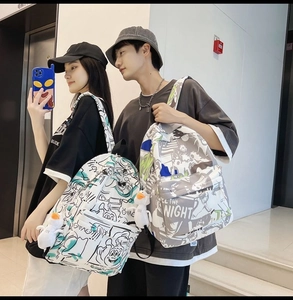 Detail of couple wearing graffiti print backpacks with cartoon duck charms and street style