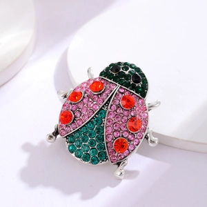 Macro shot of silver insect ladybug brooch with pink and green rhinestone detailing