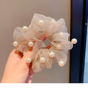 Close-up of beige organza scrunchie featuring elegant white pearls and soft ruffles