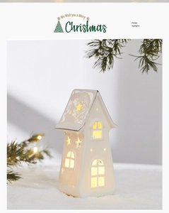 Close-up of white ceramic Christmas house with star cutouts and warm glowing light