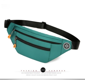 Detailed view of teal oxford fabric waist bag with orange zippers and dual compartments