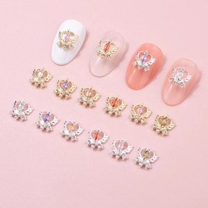 Detailed view of crown and heart nail charms with colorful zircons on pink background