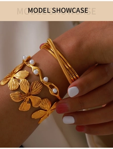 Close-up of 18K gold-plated bangle set featuring textured metal, pearls and floral details