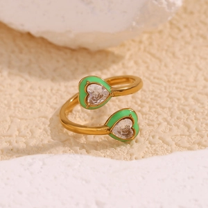 Close-up of gold plated heart ring with green enamel and sparkling zircon on white rock