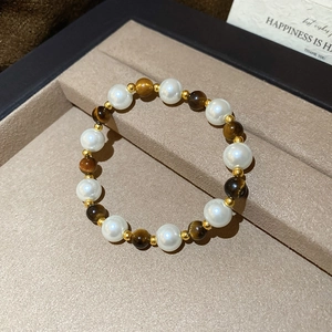 Detail of vintage tiger eye and pearl beaded bracelet with gold accents in a gift box