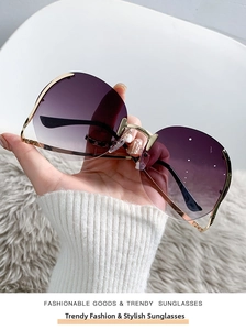 Detail of rimless sunglasses with purple gradient lenses and gold metal temples