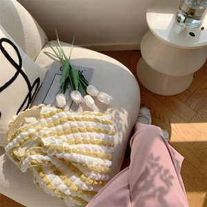 Detail of yellow and white checkered seersucker shoulder bag with 3D wave texture