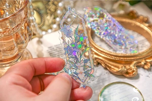 Close-up of holographic PVC bookmark with embossed purple flower and aurora glitter effect