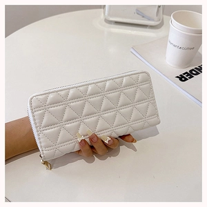 White quilted long wallet with gold zipper on a coffee table in a lifestyle setting