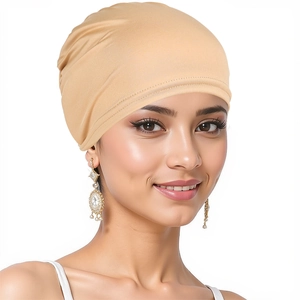 Close-up of soft and elastic beige turban hat worn by a smiling model on plain background