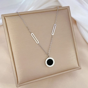Detail of silver titanium steel necklace featuring a Roman numeral pendant on a beige display