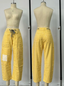 Detailed view of yellow and white striped casual pants with drawstring waist and pockets