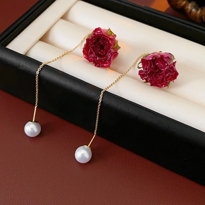 Gros plan de boucles d'oreilles rose rouge avec perles blanches sur chaînes dorées