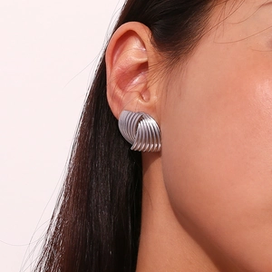 Macro view of geometric striped spiral silver earrings showing artistic metal texture