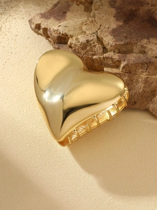 Polished golden metal heart-shaped hair claw clip on natural stone background