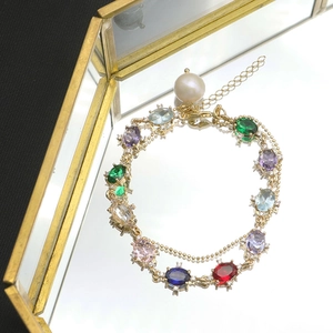 Detailed close-up of a gold gemstone bracelet with pearls on a mirror tray background