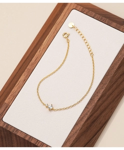 Macro shot of gold silver bracelet with zircon stones on a minimalist wooden tray