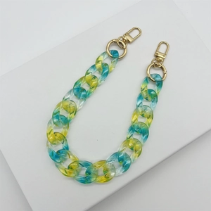 Gelb-blaue Acrylkette mit Gold-Karabinerverschlüssen auf einem weißen Ständer für Taschen