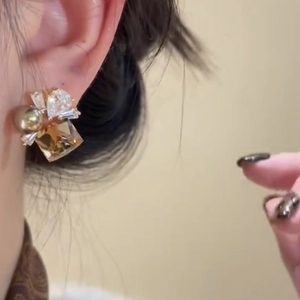 Close-up of vintage geometric gold earrings with pearl and zircon inlay on model