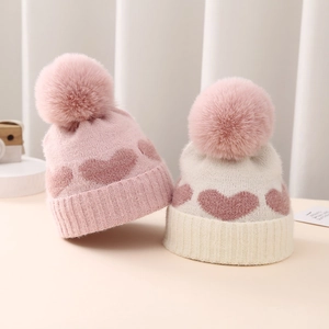 Detailed close-up of soft knit texture and pink heart patterns on baby winter hats